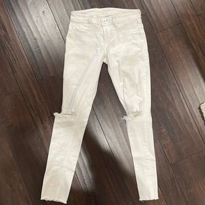DL1961 raw hem white skinny jeans with distressing at both knees and throughout